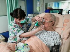 a nurse wiping an elderly patient’s mouth